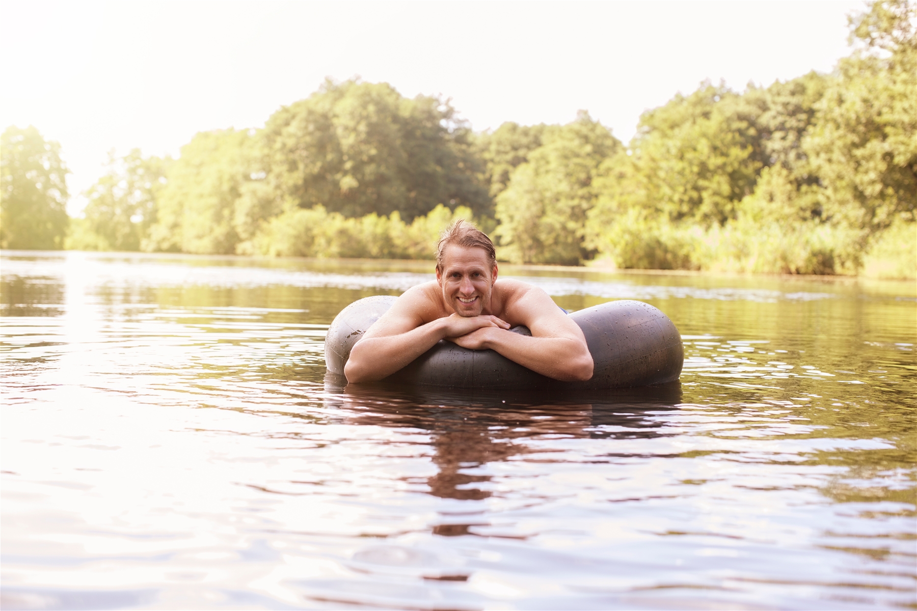 Man Floating in Innertube on River